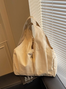 Grand sac fourre-tout en toile beige avec design plissé sur un canapé en cuir noir