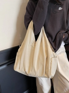 Sac fourre-tout minimaliste en toile beige pour femme porté à l'épaule au quotidien