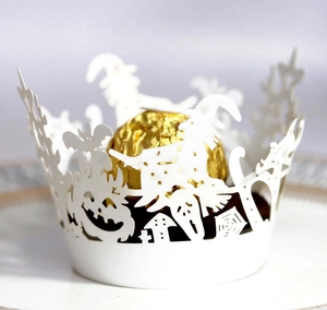 Detail showing white laser-cut Halloween cupcake wrapper with witch and pumpkin designs