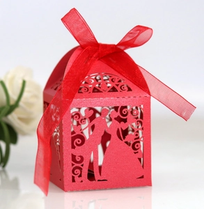 Macro detail of red laser-cut candy box with bride and groom silhouette and ribbon