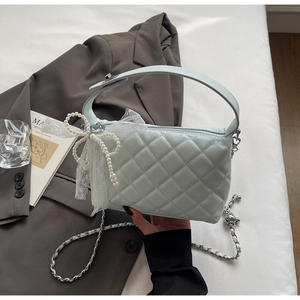 Detail of light blue quilted bag with pearl bow, lace trim and silver metal clasp