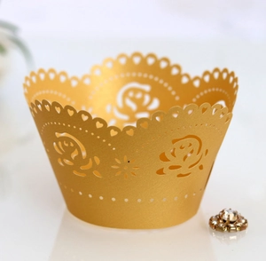 Macro view of laser-cut rose patterns on matte golden cupcake wrappers for weddings