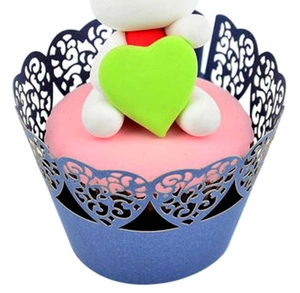 Macro detail of laser-cut heart pattern on dark blue cupcake wrapper with vine designs
