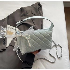 Detail of mint blue quilted bag featuring a large pearl bow and elegant lace trim