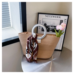 Detailed macro view of silver round metal handles and printed silk scarf on woven tote bag