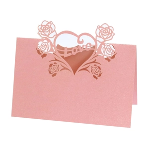 Close-up of pink laser-cut wedding place card with rose design and Love cutout