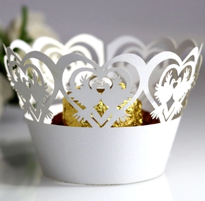 Elegant white laser-cut cupcake wrappers with heart and dove patterns for wedding decor