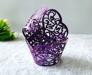 Detail of purple laser-cut cupcake wrapper with butterfly and filigree flower patterns