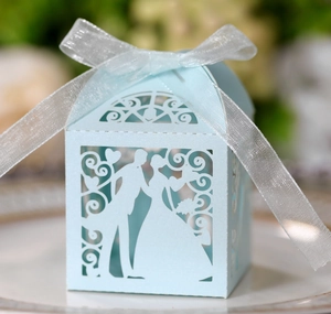 Detail of light blue laser-cut wedding candy box with silhouette and white ribbon