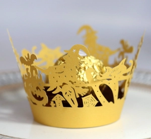 Laser-cut Halloween cupcake wrapper with witch and pumpkin patterns on gold pearlescent paper