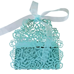 Close-up of laser-cut rose patterns on a mint blue wedding candy box with ribbon