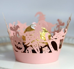Detail of pink laser-cut cupcake wrapper featuring Halloween witch and pumpkin designs