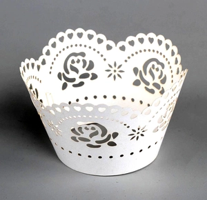 Detail of white laser-cut cupcake wrapper featuring intricate rose and heart patterns
