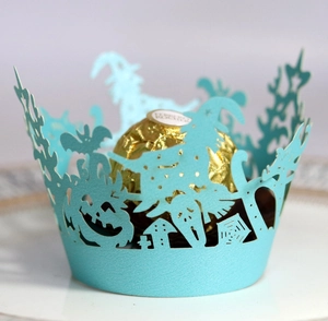 Detail of light blue laser-cut Halloween cupcake wrapper featuring witch and pumpkin motifs
