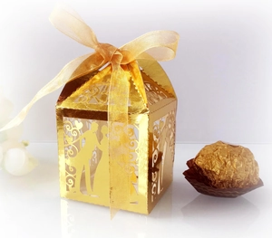 Laser-cut gold wedding favor box with romantic silhouette and elegant ribbon detail