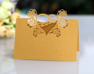 Macro detail of laser-cut gold wedding place card with elegant rose and heart pattern