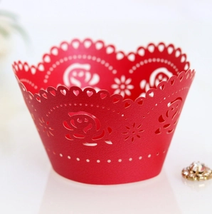 Macro shot of laser-cut red cupcake wrapper with elegant rose and heart hollow patterns