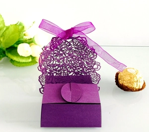 Detail of purple laser-cut rose wedding favor box with silk ribbon and gold chocolate