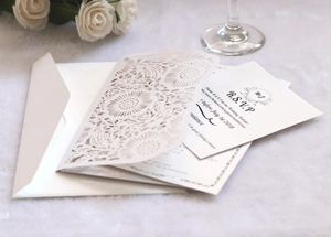Dettaglio invito di nozze con intaglio laser floreale avorio su velluto bianco elegante