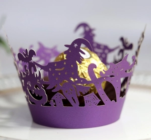 Macro view of purple laser-cut Halloween cupcake wrapper with witch and pumpkin detail