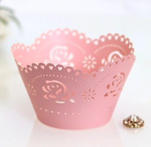 Close-up of pink laser-cut cupcake wrapper with floral rose patterns and lace details