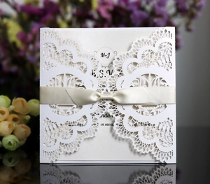 Detailed laser cut lace wedding invitation with ivory satin bow and RSVP card