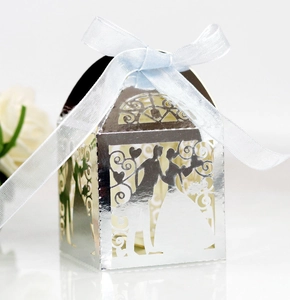 Detail of silver laser-cut wedding candy box with groom and bride silhouette and blue ribbon