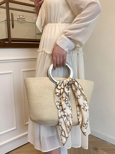 Straw tote bag with metal handles and silk scarf detail in casual summer style