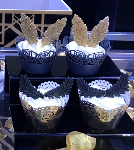 Detailed laser-cut heart pattern cake liners and feather toppers on elegant stand