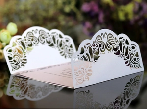 Détail d'invitation de mariage découpée au laser avec carte rose et reflet sur miroir