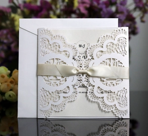 Detailed laser-cut wedding invitation with ivory lace sleeve and elegant satin bow