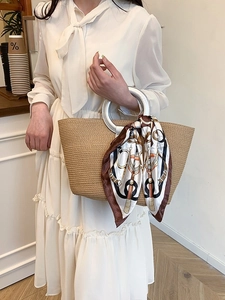 Brown woven straw tote bag with silver round metal handle and decorative silk scarf detail