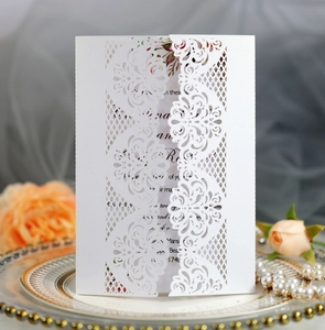 Detail of laser-cut white wedding invitation with lace floral pattern and pearlescent paper