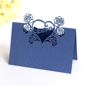 Macro detail of dark blue laser-cut heart seat card with intricate Love rose pattern