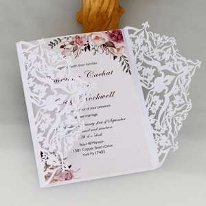 Intricate laser-cut wedding invitation with elegant floral patterns and champagne finish
