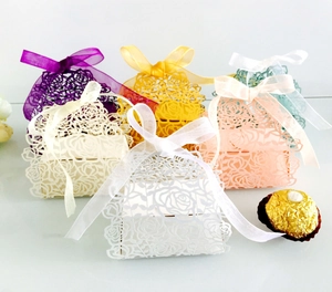 Macro view of laser-cut rose hollow favor boxes with elegant organza ribbons in various colors