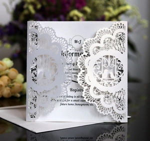 Macro detail of laser-cut wedding invitation featuring intricate lace and lovebirds design