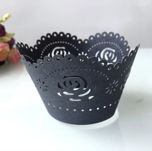Detail showing black laser-cut cupcake wrapper with intricate rose patterns and wavy edges