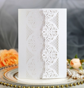 Detail showing the intricate laser-cut floral pattern of the white invitation card