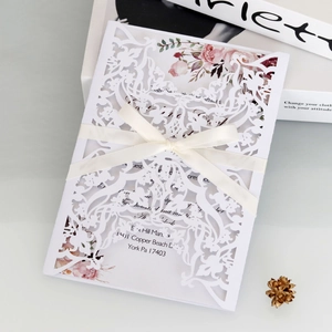 Detailed laser-cut champagne wedding invitation with cream ribbon and floral inner card