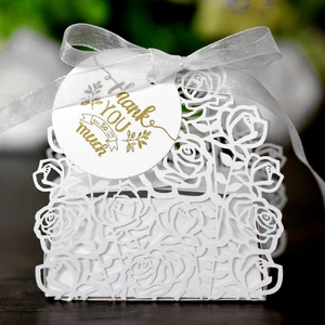 Macro detail of laser-cut rose pattern on white candy box with white ribbon and thank you tag