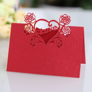 Detail of red laser-cut place card with rose heart design and Love typography