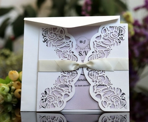 Détails de motifs floraux découpés au laser sur une invitation avec ruban de soie crème