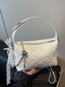 Elegant white quilted chain bag with pearl charm and lace bow in a hand-held display
