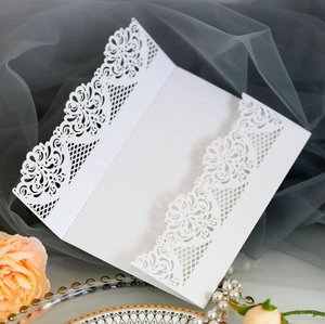 Close-up of laser-cut white floral lace invitation card with elegant mesh details