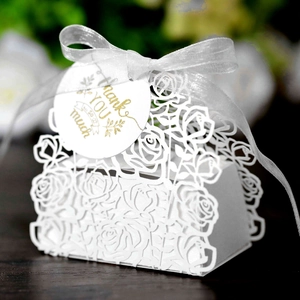 Macro view of white laser-cut rose hollow favor box with a silk ribbon and Thank You tag