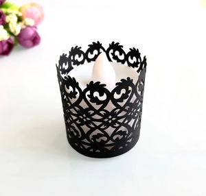 Detail of laser-cut black hollow candle wrap with vine pattern and LED tea light