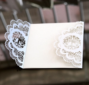 Detail of laser-cut wedding invitation featuring elegant bird motifs and lace patterns