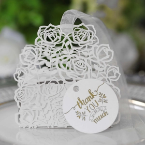 Close-up of laser-cut rose hollow favor box with white ribbon and a gold thank you tag
