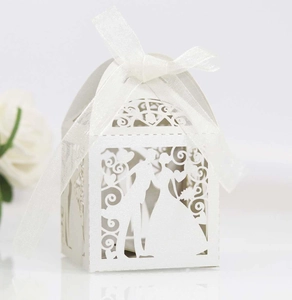 Detailed laser-cut silhouette of bride and groom on white candy box with silk ribbon